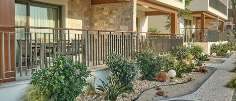 A multi-story hotel with balconies, stone facade, and a landscaped pathway.