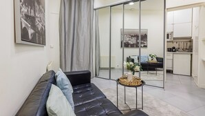 Una sala moderna con un sofá de cuero, una mesita auxiliar y un amplio ventanal corredizo que da a una zona de cocina.