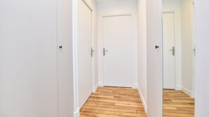 A narrow hallway with white walls and wooden flooring, leading to a closed door at the end. - Authentic Apartment - 2br/8p - Near Opera Garnier (Paris)