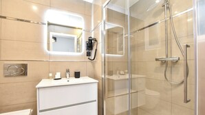 A modern bathroom with a glass-enclosed shower, a white vanity with a mirror, and a toilet. - Authentic Apartment - 2br/8p - Near Opera Garnier (Paris)