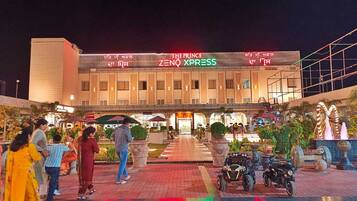 A hotel named 'The Prince Zenith Xpress' with a modern facade, a covered entrance, and a landscaped courtyard with decorative elements.