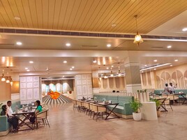 Un amplio hall de hotel con zonas de estar, suelo a cuadros y un elemento decorativo central.