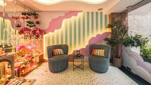 A cozy room with two grey armchairs, a small table, and a decorative wall with vertical stripes and cloud patterns.