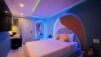 A modern bedroom with a large bed, a bedside table, a nightstand, and a mirror.