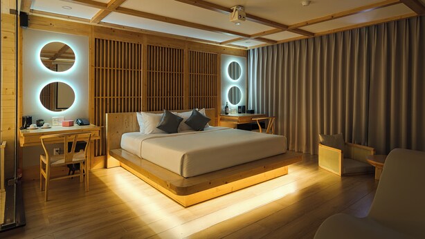 Un dormitorio moderno con cama de madera, mesitas de noche, escritorio y silla.