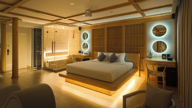 A modern bedroom with a large bed, a desk, and a glass shower area.