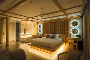 Quarto moderno com uma cama grande, uma escrivaninha e área de chuveiro em vidro.