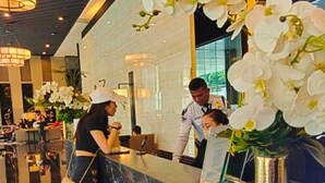 A reception area with a marble counter, white orchids, and a modern interior design. - Rent Xpress Online Heart of Makati (Makati)
