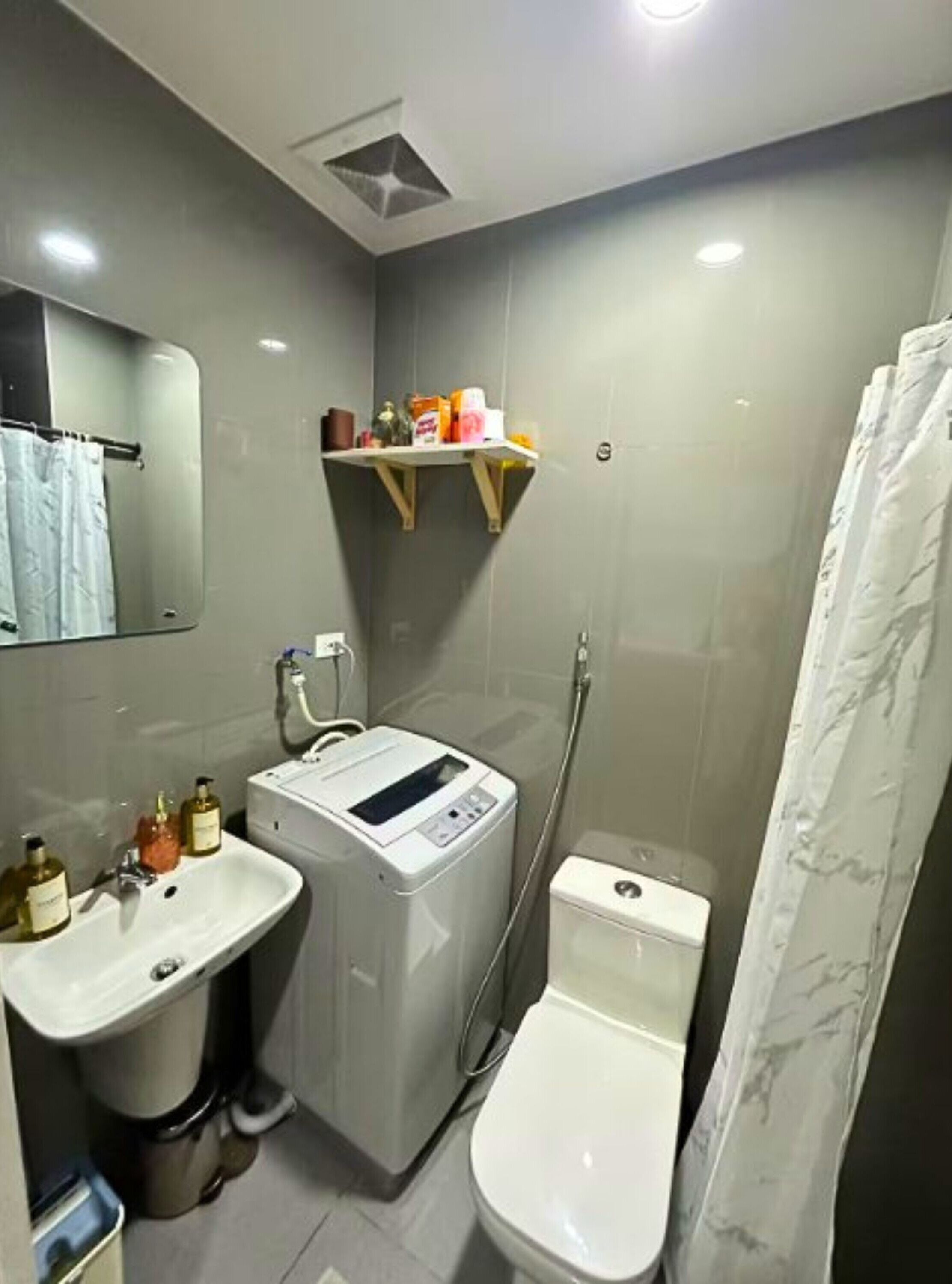 Un baño pequeño con lavadora, inodoro, lavamanos y cortina de ducha.