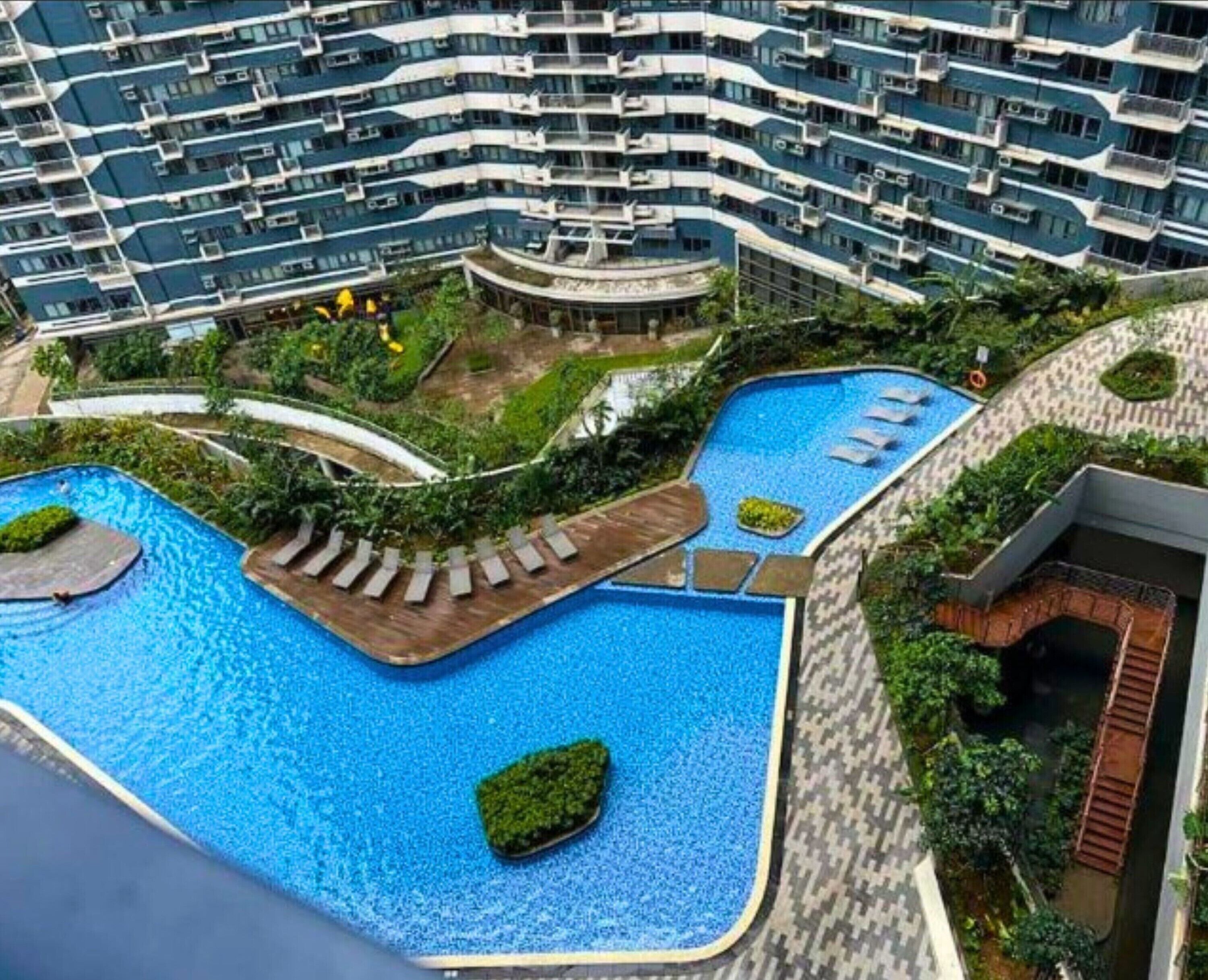 Un immeuble résidentiel doté de nombreux balcons et d’un espace piscine avec des chaises longues.