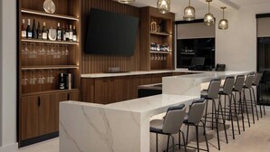 A modern bar area with a marble countertop, bar stools, and a variety of bottles and glasses on shelves. - Fairfield by Marriott Inn & Suites Forrest City (Forrest City)