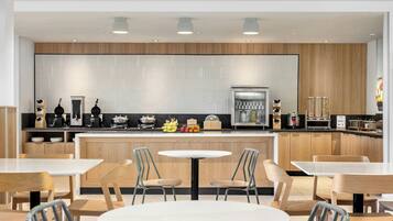 A modern kitchen with wooden cabinets, a central island, and a seating area with tables and chairs.
