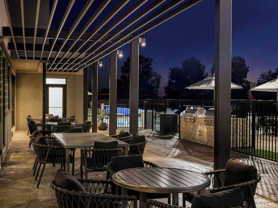 An outdoor patio area with tables and chairs, a grill, and a view of the pool.