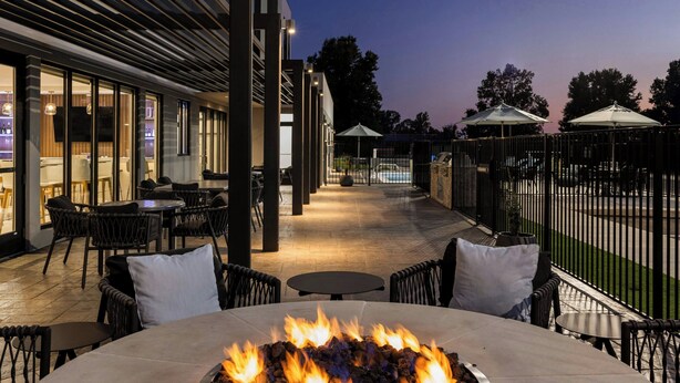 An outdoor patio area with a fire feature, tables, chairs, and umbrellas. - Fairfield by Marriott Inn & Suites Forrest City (Forrest City)