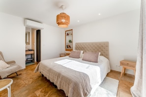 Een slaapkamer met een groot bed, een nachtkastje, een stoel, een hanglamp en een kledingkast.