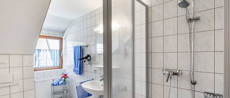 A modern bathroom with a shower, a sink, and a window.
