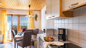 A compact kitchen with a dining area, a microwave, a coffee maker, and a view through the window. - Apartment '1' with Mountain View, Shared Garden and Wi-Fi (Owingen)