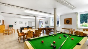 A pool table with balls, wooden chairs, and tables in a room with white walls and large windows. - Apartment '1' with Mountain View, Shared Garden and Wi-Fi (Owingen)