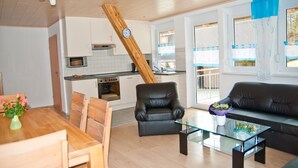 A modern kitchen with white cabinets, a wooden ceiling, and a dining area with a wooden table and chairs. - Holiday Apartment '3' with Mountain View, Shared Garden and Wi-Fi (Owingen)