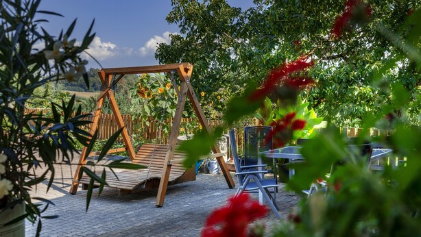 A wooden swing set, a paved patio, and a table with chairs. - Holiday Apartment '3' with Mountain View, Shared Garden and Wi-Fi (Owingen)