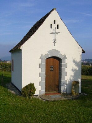 Een kleine witte kerk met een houten deur en een kruis erboven.