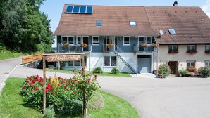 A two-story building with a sloped roof, a wooden deck, and a sign that reads 'Hausberghof.' - Holiday Apartment '3' with Mountain View, Shared Garden and Wi-Fi (Owingen)