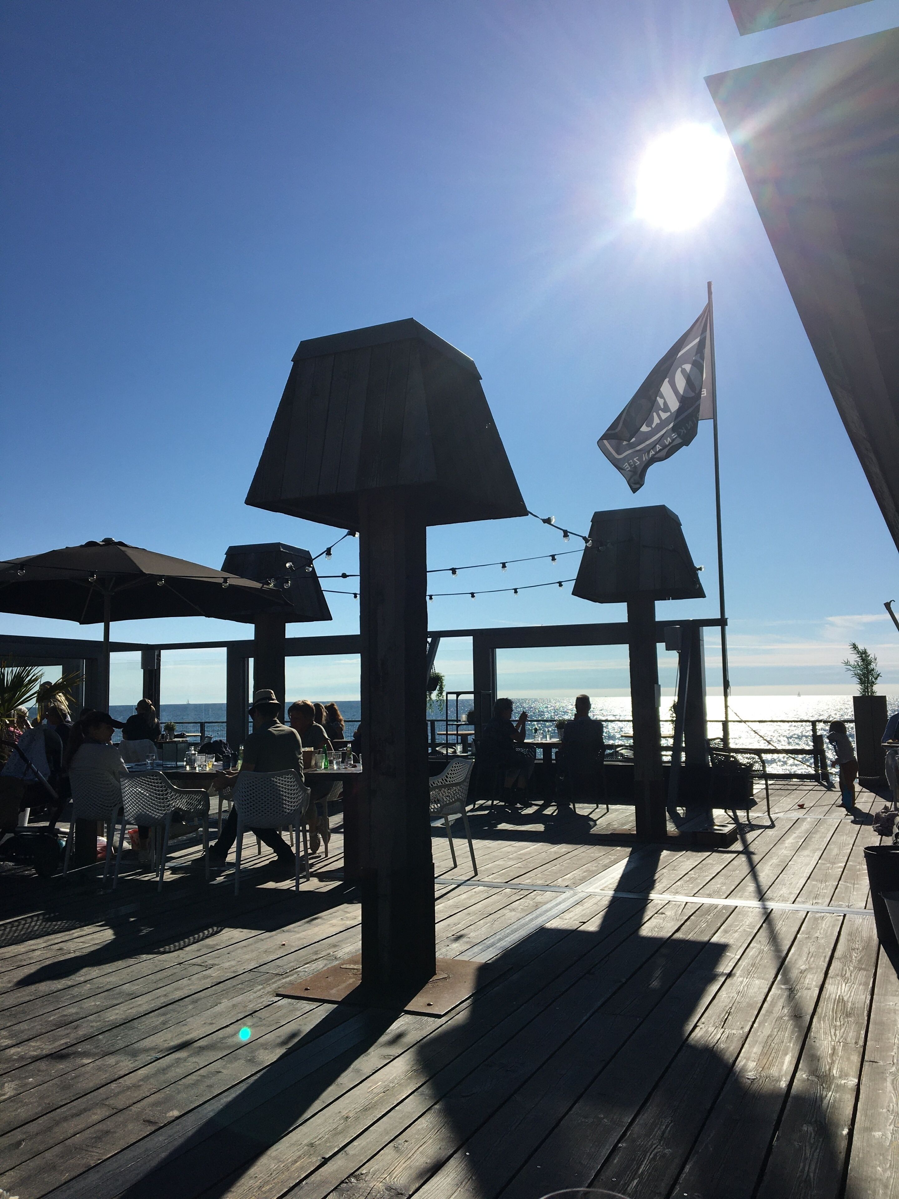 An outdoor seating area with umbrellas and tables, overlooking a body of water.