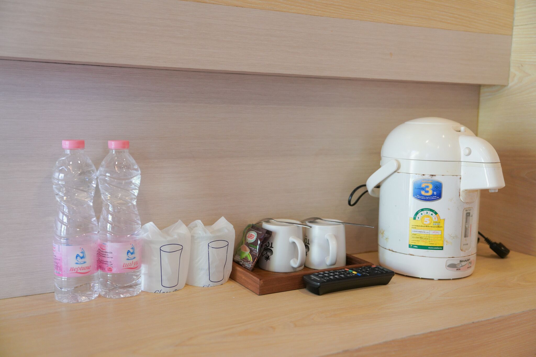 Un coin cuisine équipé d’une machine à café, de deux bouteilles d’eau, d’une télécommande et d’un plateau contenant des tasses et une tasse.
