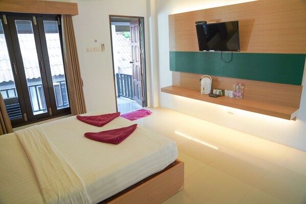 Een hotelkamer met een bed, een aan de muur bevestigde televisie en een klein kastje met toiletartikelen.