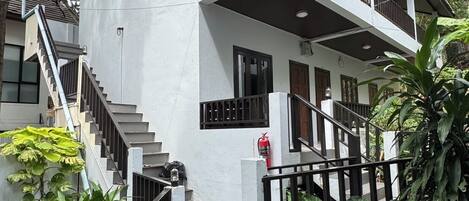 Un edificio de dos pisos con un balcón, una escalera y un extintor.