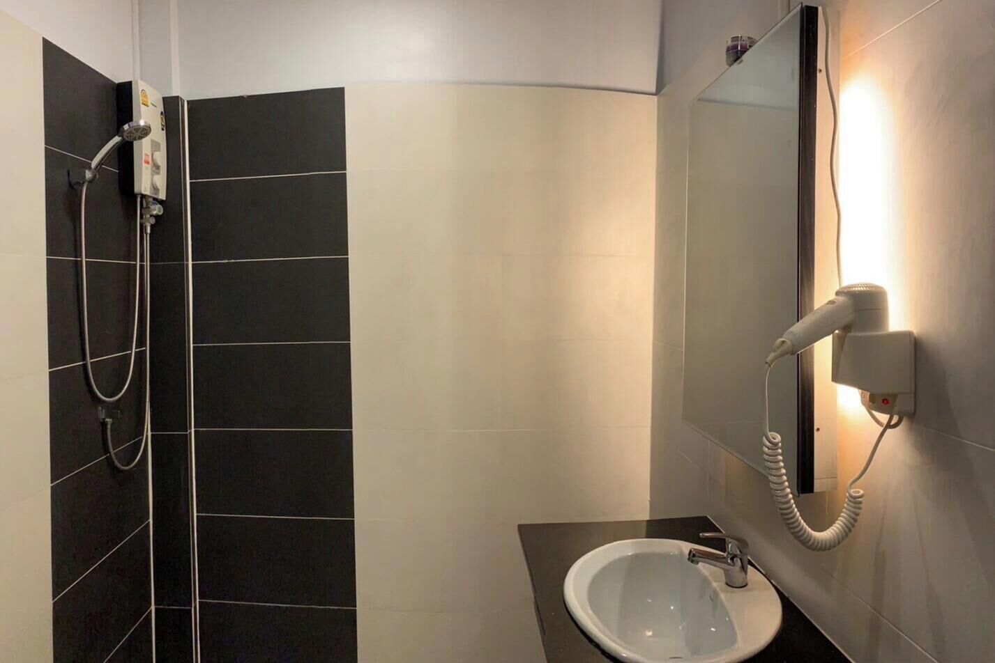 Une salle de bain avec des carreaux noirs et blancs, un lavabo, un miroir et un téléphone fixé au mur.