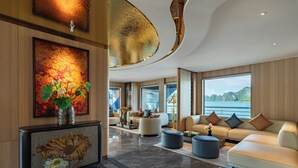 Un vaste espace de vie agrémenté d’une grande fenêtre, d’un ensemble de canapés et d’un vase décoratif contenant des fleurs.