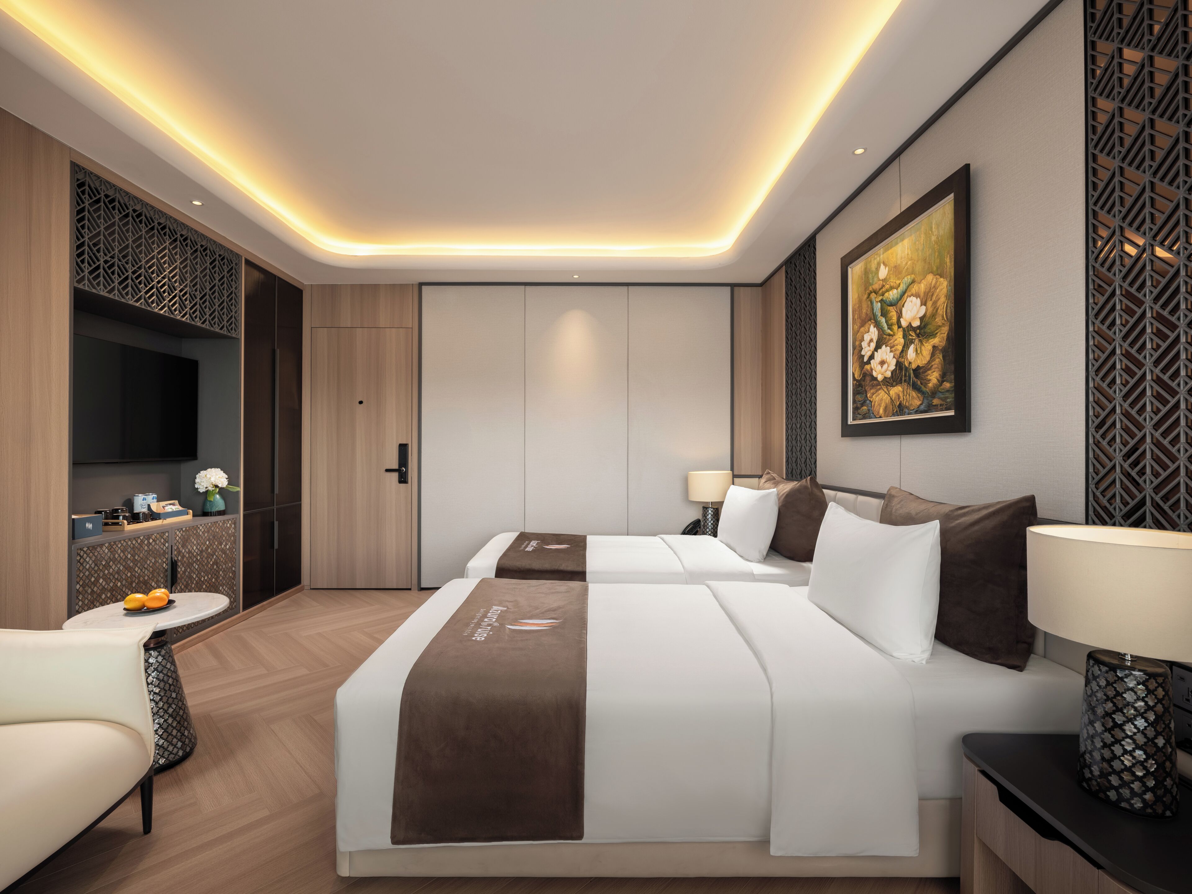 A modern hotel room with a large bed, bedside tables, a TV, and a decorative wall panel.