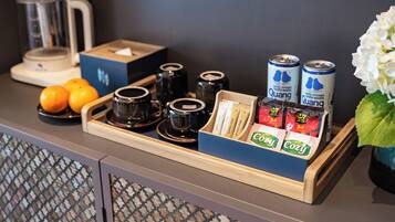 Un plateau contenant des tasses de café, des oranges, des sachets de thé et des canettes de la boisson Quang, posé sur le comptoir d’un hôtel.