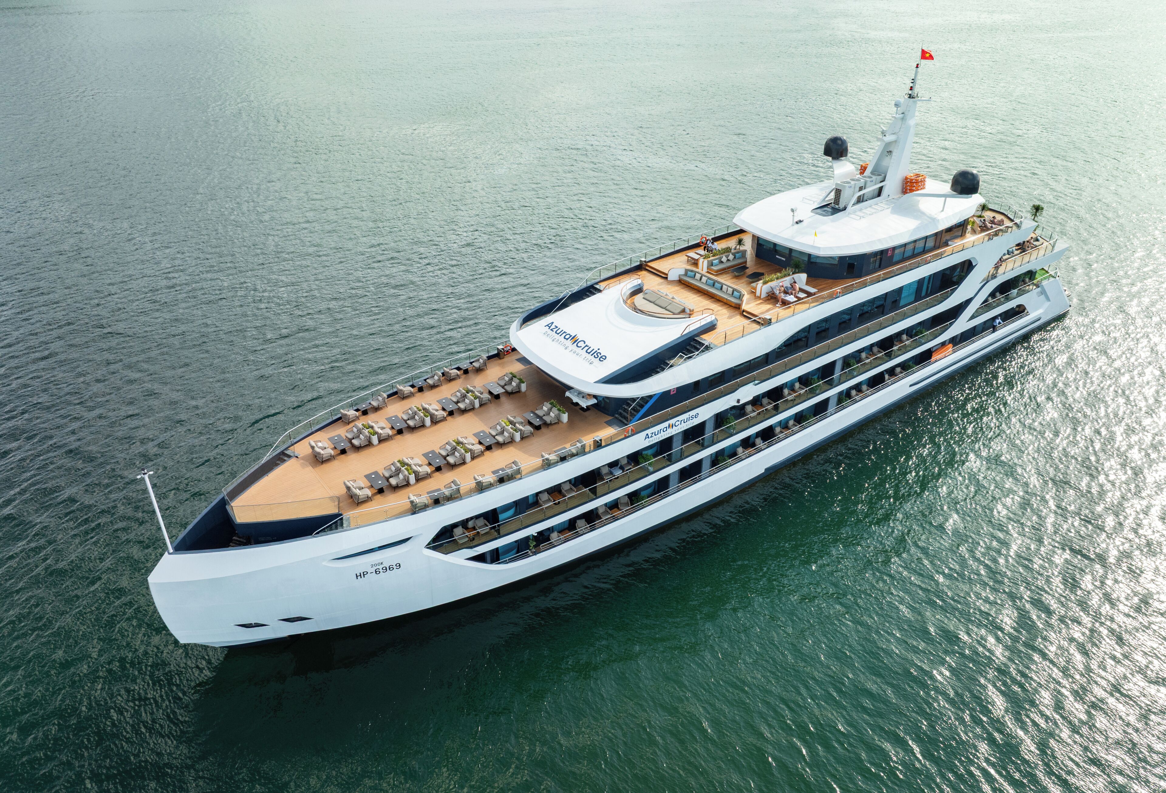 Ein großes Kreuzfahrtschiff mit mehreren Decks, Sitzbereichen im Freien und einer überdachten oberen Deck.