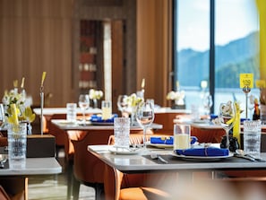 A restaurant with tables set for dining, clear glassware, and a view of the outdoors. - Azura Cruise (Ha Long)