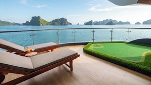 Une terrasse avec des chaises longues, une petite table avec des boissons, et une vue sur la mer et les îles.