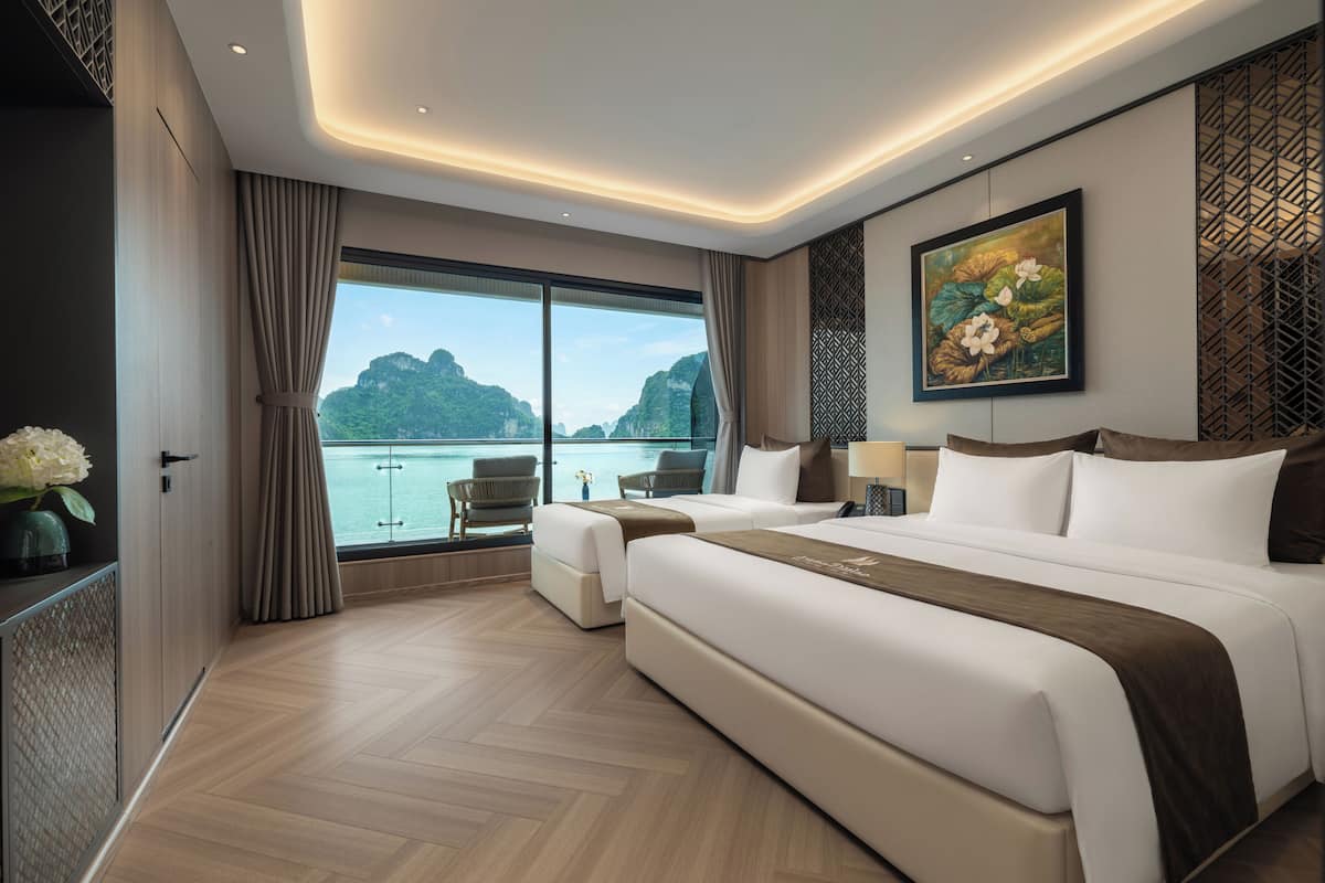 A modern hotel room with a large bed, a seating area with a view of the sea, and a decorative wall panel.