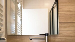 Ein modernes Badezimmer mit einem Holz-Waschtisch, einem Spiegel und einem Handtuchhalter.