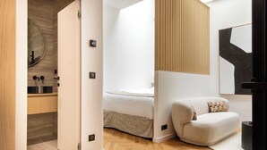 A modern bedroom with a bed, a sofa, a wooden floor, and a wall-mounted artwork. - Cosy and Modern Apt-jardin de Luxembourg (Paris)
