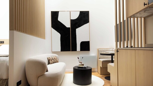 A modern living room with a sofa, a round black coffee table, and a large abstract painting on the wall. - Cosy and Modern Apt-jardin de Luxembourg (Paris)