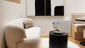 A modern living room with a white sofa, a black coffee table, and two abstract paintings on the wall. - Cosy and Modern Apt-jardin de Luxembourg (Paris)