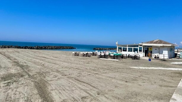 A beachside building with outdoor seating and a view of the ocean. - Casa Romano SeaFront (Fiumicino)