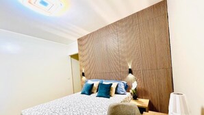 A modern hotel room with a large bed, a wooden headboard, a desk, and a chair. - Casa Romano SeaFront (Fiumicino)