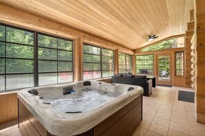 A wooden cabin interior with a hot tub, large windows, and a dining area. - Fiddler Lake Resort - Bear 25 (Mille-Isles)