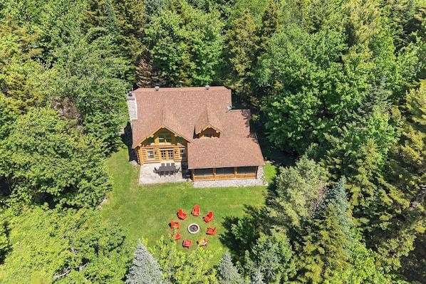 A lodge with a central building surrounded by a forest, featuring a circular outdoor seating area.