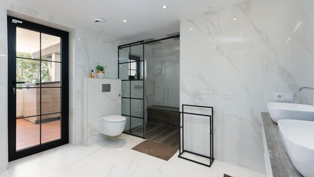 Et moderne badeværelse med toilet, bruser og vask.
