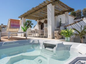 Ein Poolbereich auf dem Dach mit Whirlpool, Liegestühlen und einer Pergola.