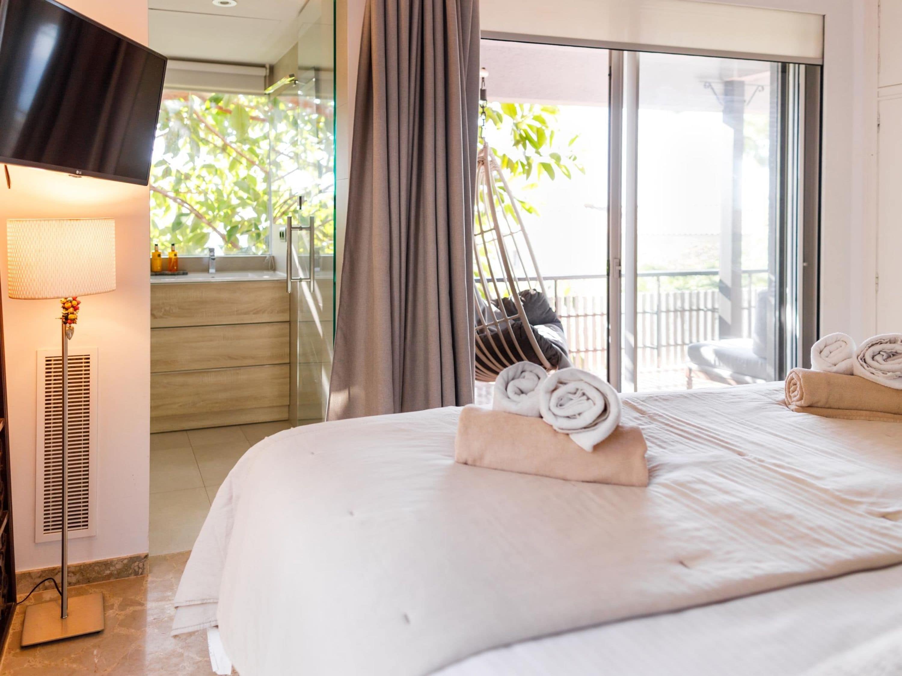 Una habitación de hotel con cama, televisión, lámpara y vistas al exterior.