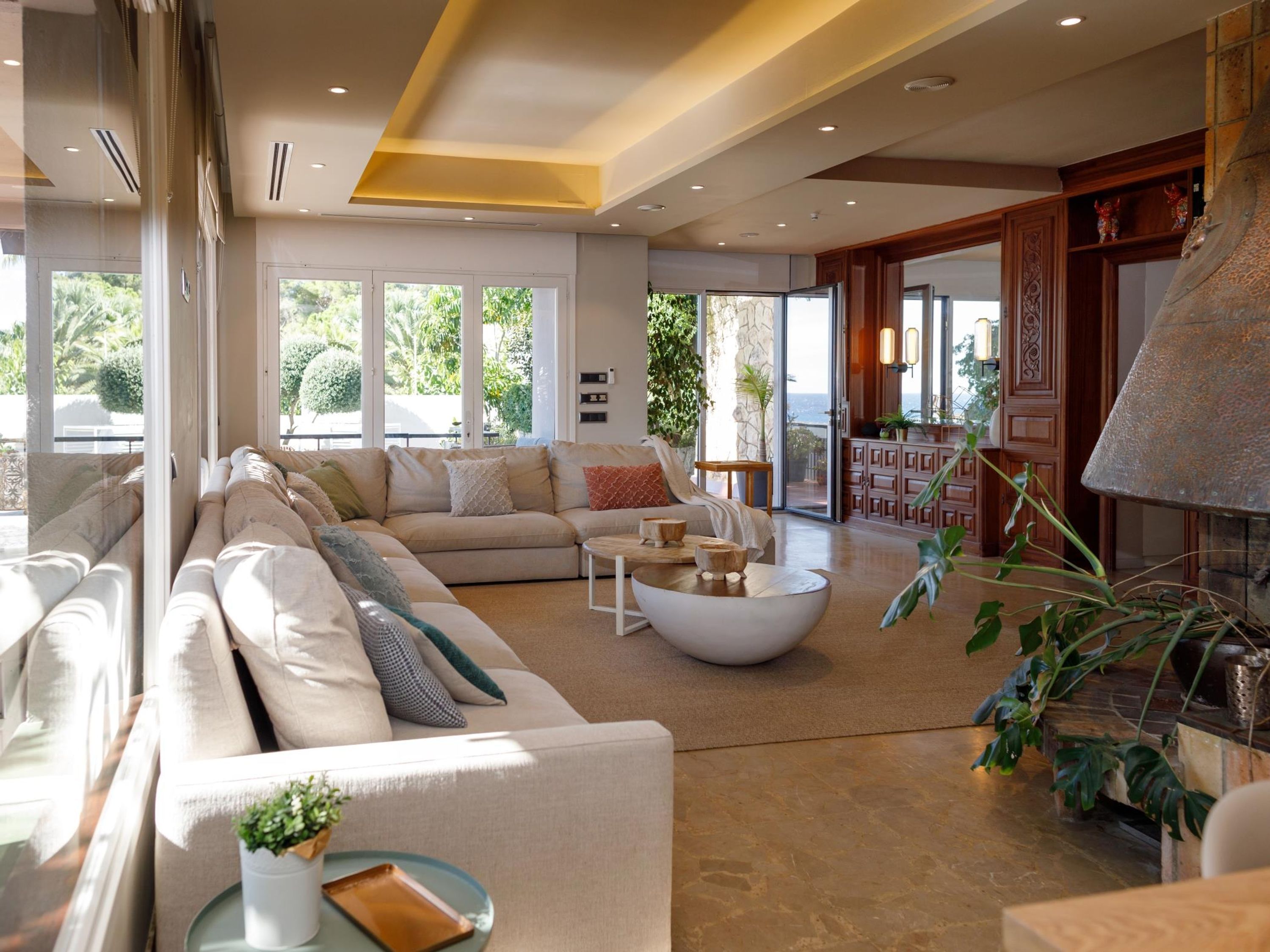 Un salón amplio con un sofá modular grande, una mesa de centro redonda y una chimenea.
